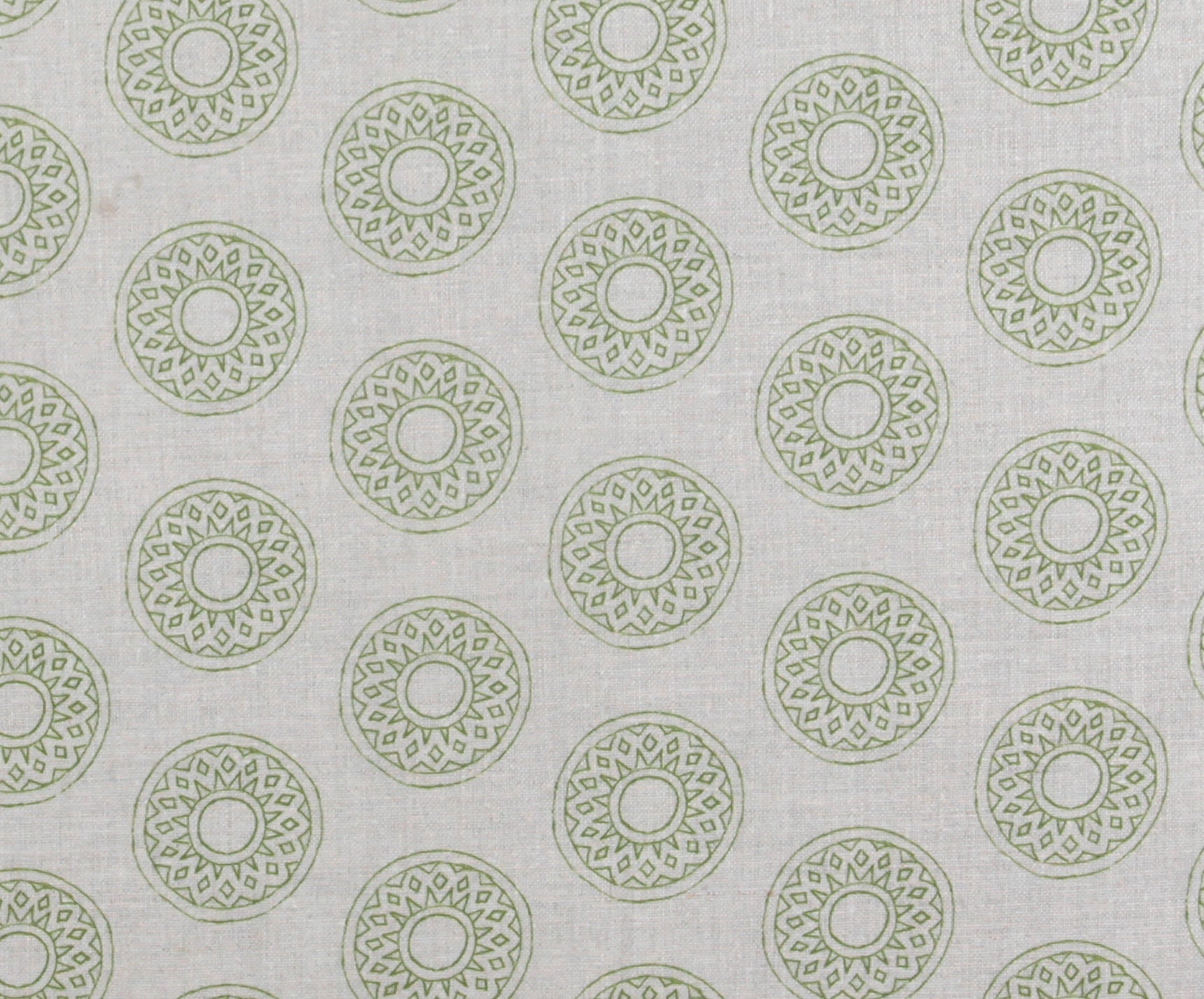 Detail of fabric in a repeating circular geometric print in green on a greige field.