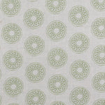 Detail of fabric in a repeating circular geometric print in green on a greige field.