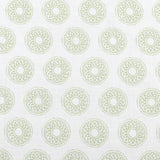 Detail of fabric in a repeating circular geometric print in green on a white field.
