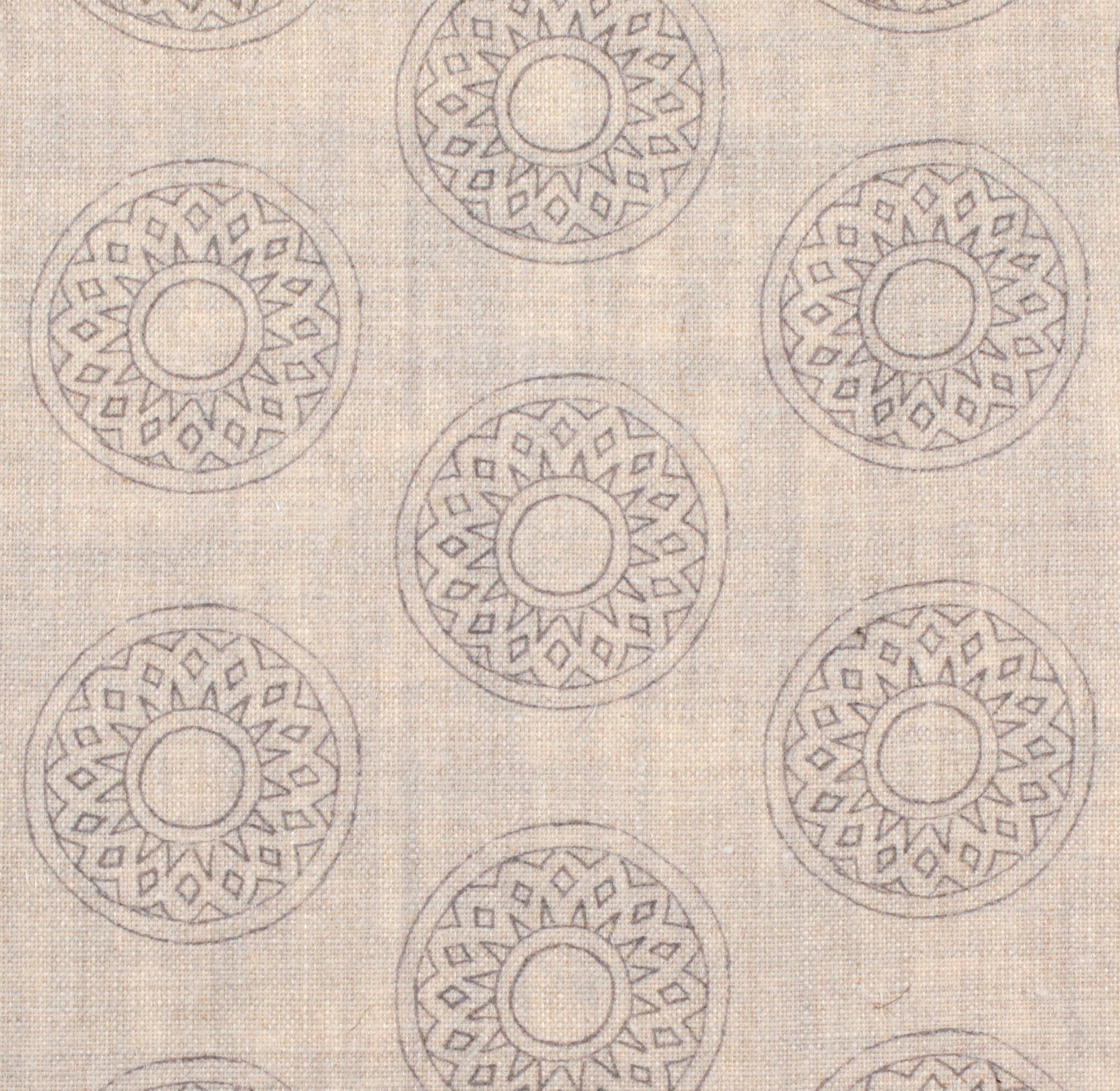 Detail of fabric in a repeating circular geometric print in light gray on a tan field.