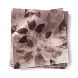 Stacked swatches of fabric in a painterly leaf print in shades of muted purple on a white background.
