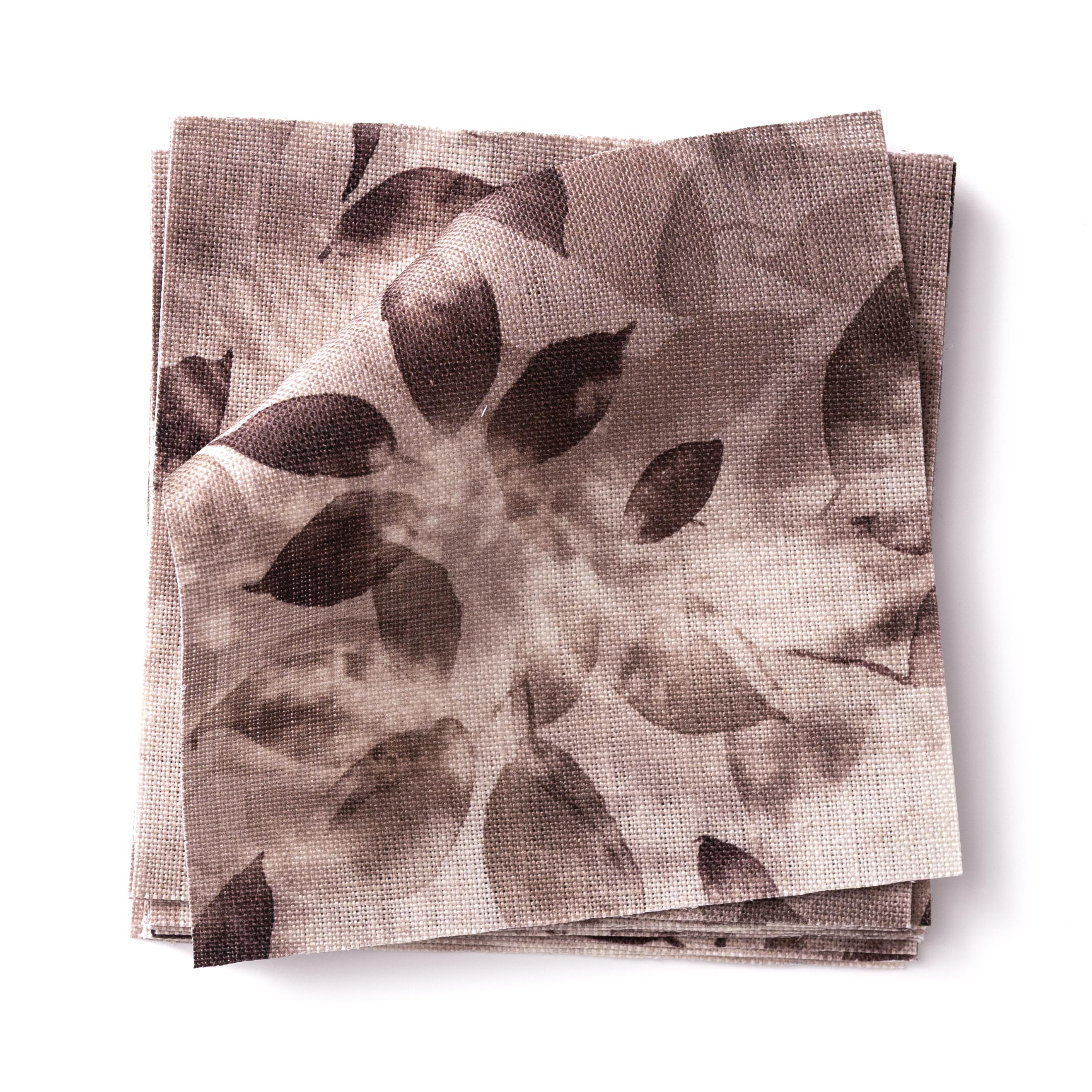 Stacked swatches of fabric in a painterly leaf print in shades of muted purple on a white background.