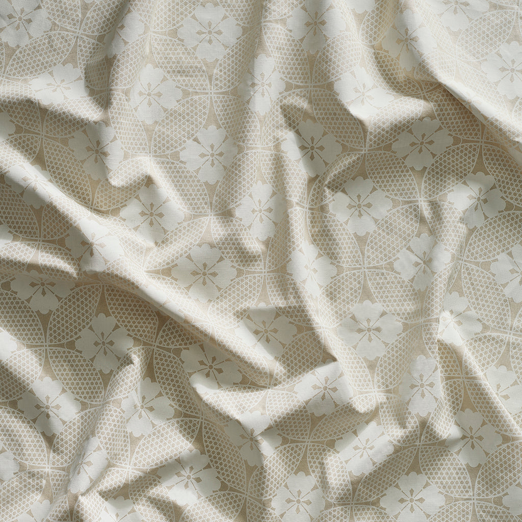 A close-up of gently draped printed linen featuring a Japanese inspired floral lattice design in white on ecru.