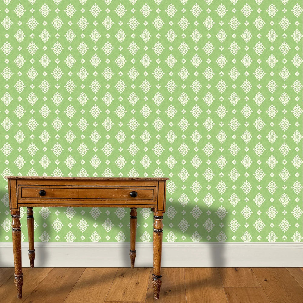 A wooden end table stands in front of a floral damask print in white on a green field.