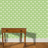 A wooden end table stands in front of a floral damask print in white on a green field.
