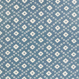 Detail of fabric in a geometric lattice print in white on a blue field.