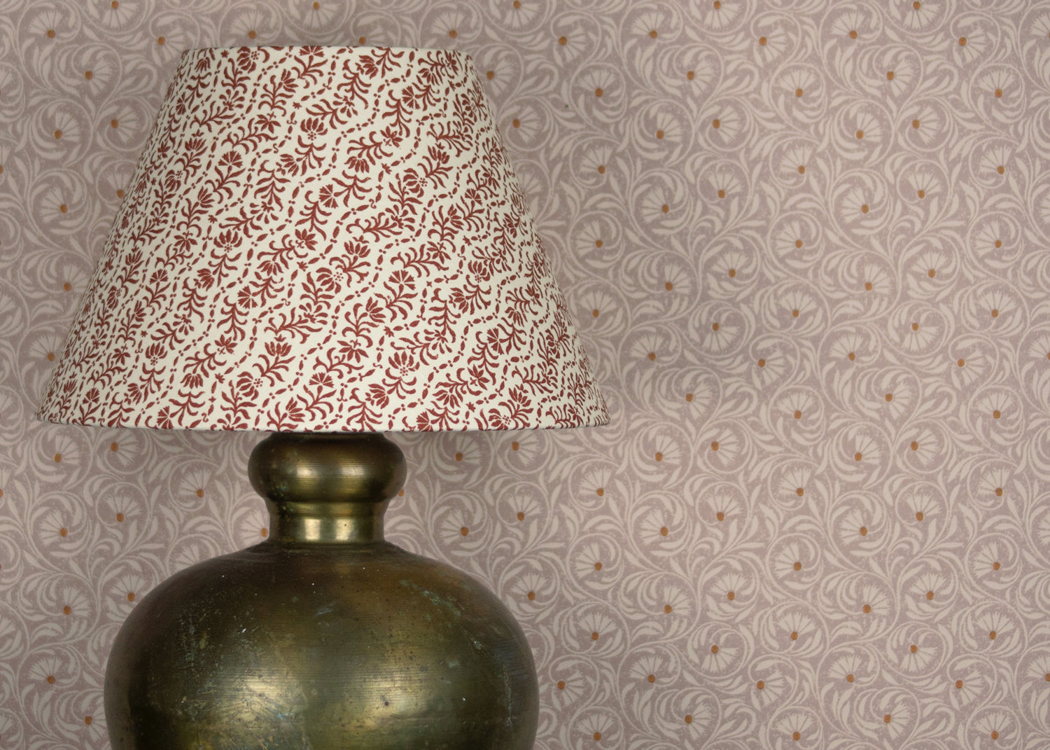 Decorative lamp against wWallpaper in a lyrical wildflower design in cream with rust accents on a lilac field. 