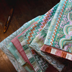 Stack of colorful fabric swatches on a wooden surface
