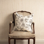 Decorative pillow on an ornate chair against a striped wall.