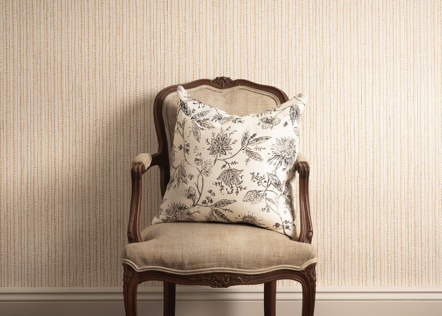 Decorative pillow on an ornate chair against a striped wall.