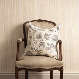 Decorative pillow on an ornate chair against a striped wall.