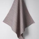 Draped woven outdoor fabric in a subtle stripe design in red and blue on a white wall. 