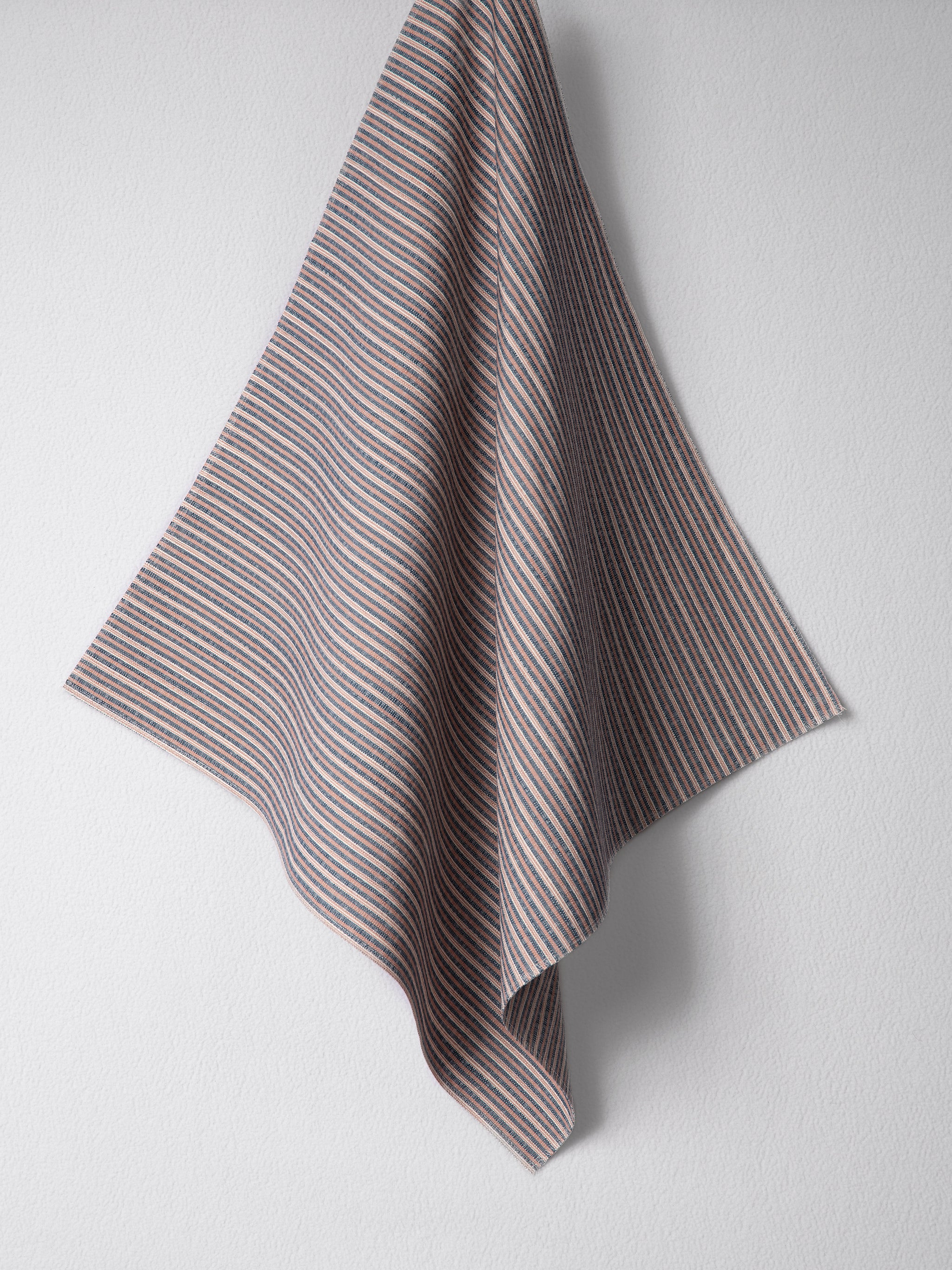 Draped woven outdoor fabric in a subtle stripe design in red and blue on a white wall. 