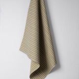 Draped woven outdoor fabric in a subtle stripe design in green and tan on a white wall. 