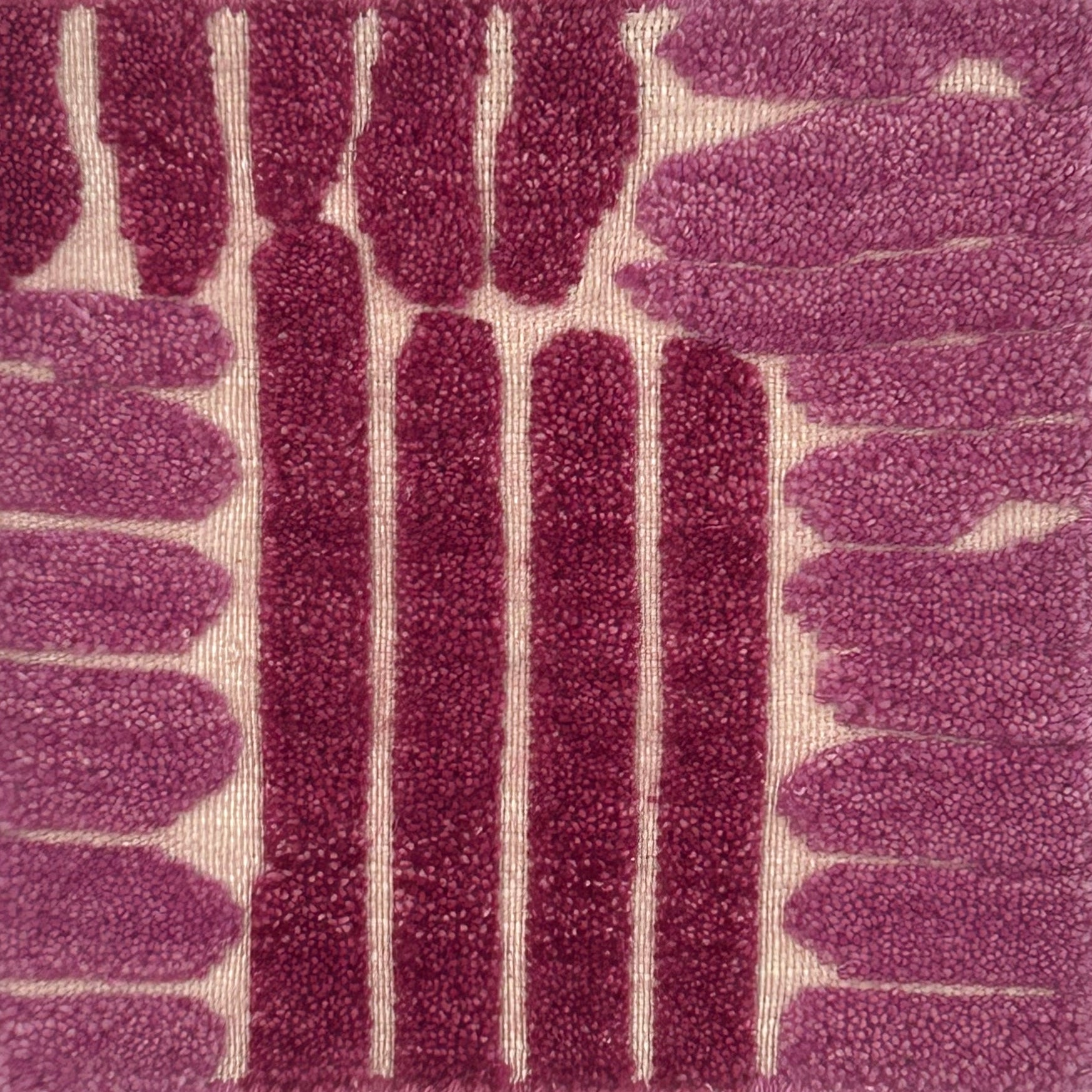 Close-up of a flatweave rug with a raised pink linear design.