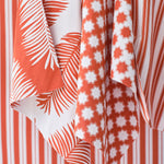 An array of bright orange and white performance fabrics in a palm print, moroccan star and simple stripe.