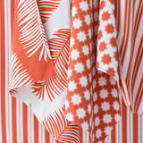 An array of bright orange and white performance fabrics in a palm print, moroccan star and simple stripe.