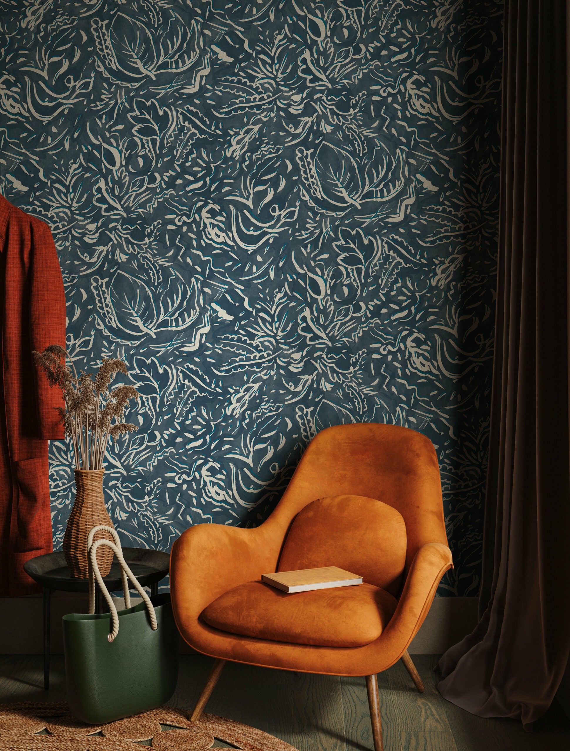 A burnt orange lounge chair in front of a wall papered in a painterly botanical print in white and blue on a navy field.