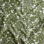 Close up of gently draped woven Indoor-Outdoor fabric with flower and leaf silhouette pattern in green on white background