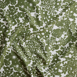 Close up of gently draped woven Indoor-Outdoor fabric with flower and leaf silhouette pattern in green on white background