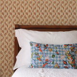 Bed with patterned headboard, floral pillow, and books on a brown striped wallpaper.