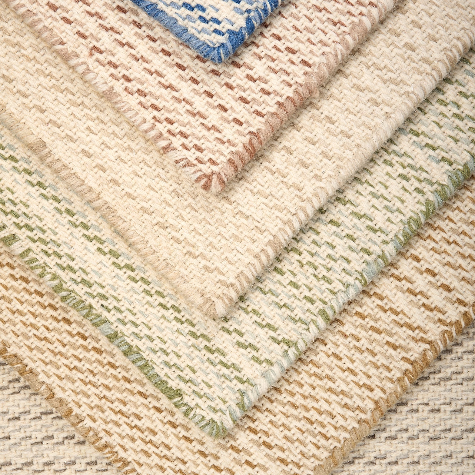 Stack of broadloom carpet samples in a subtle stripe design in taupe, ochre, green, cream, rose red and blue.