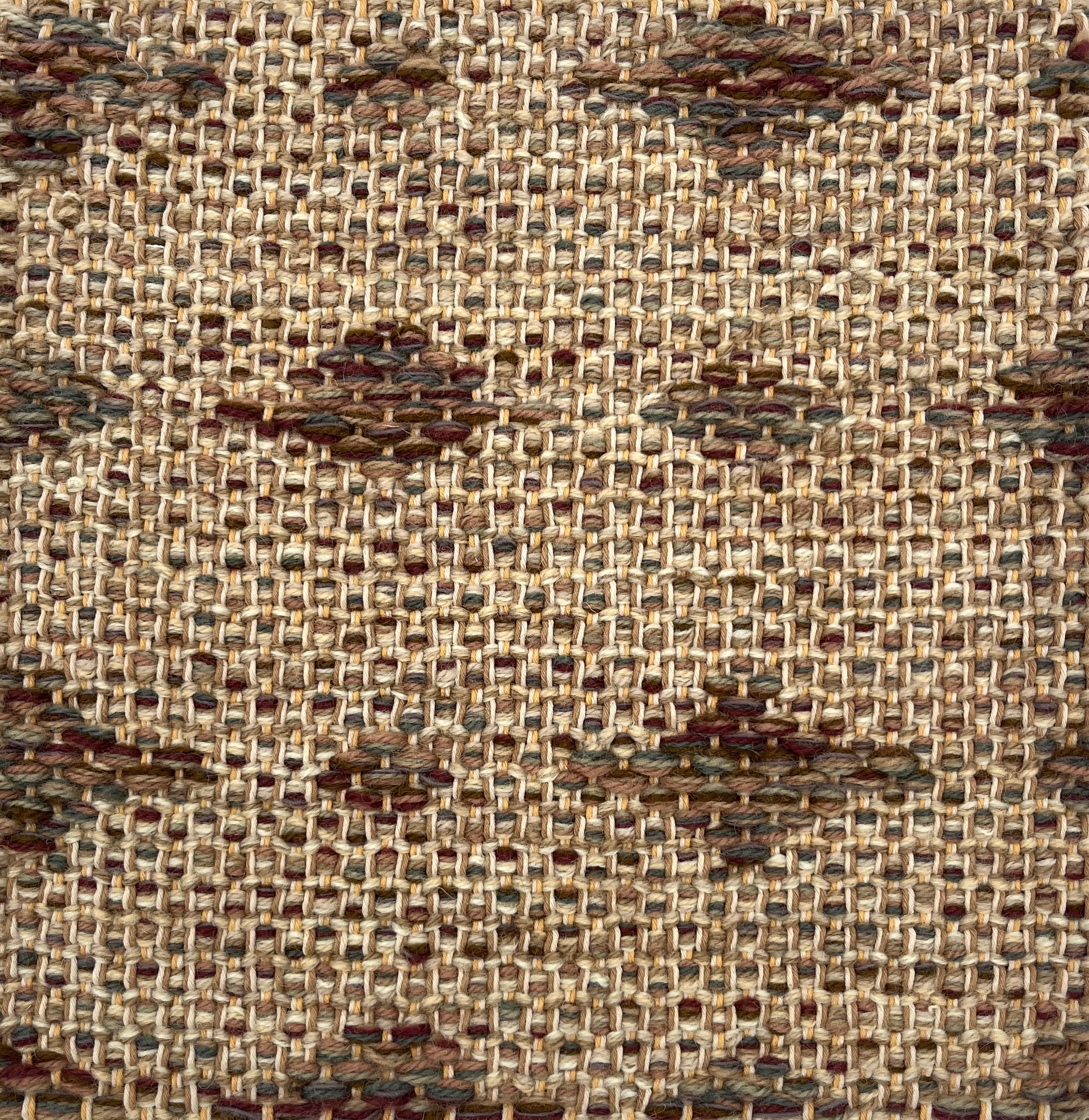 Close-up of a woven rug  with a diamond pattern in shades of brown.
