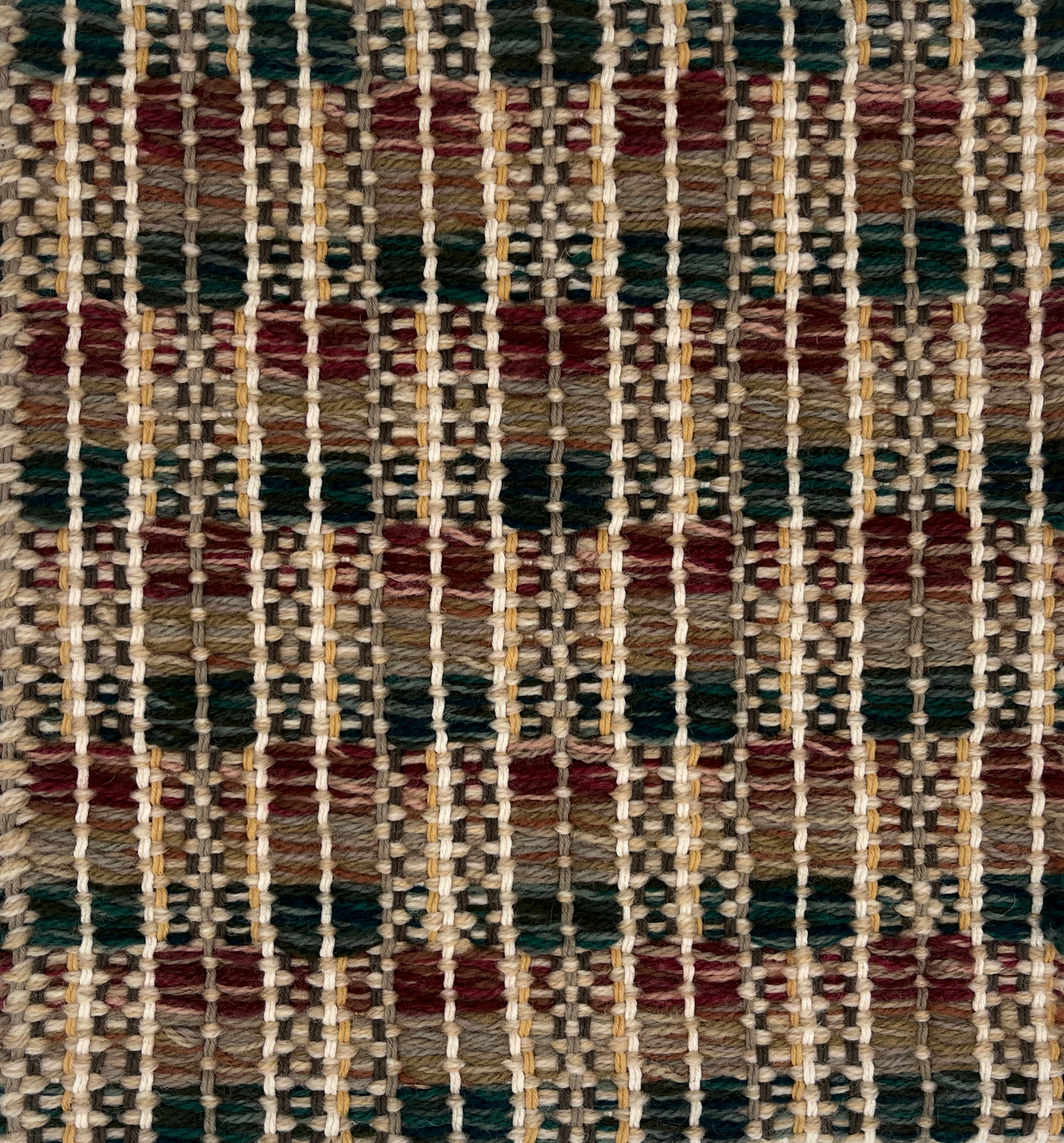 Close-up of a woven rug  with a geometric checker pattern in brown, green and brick red.