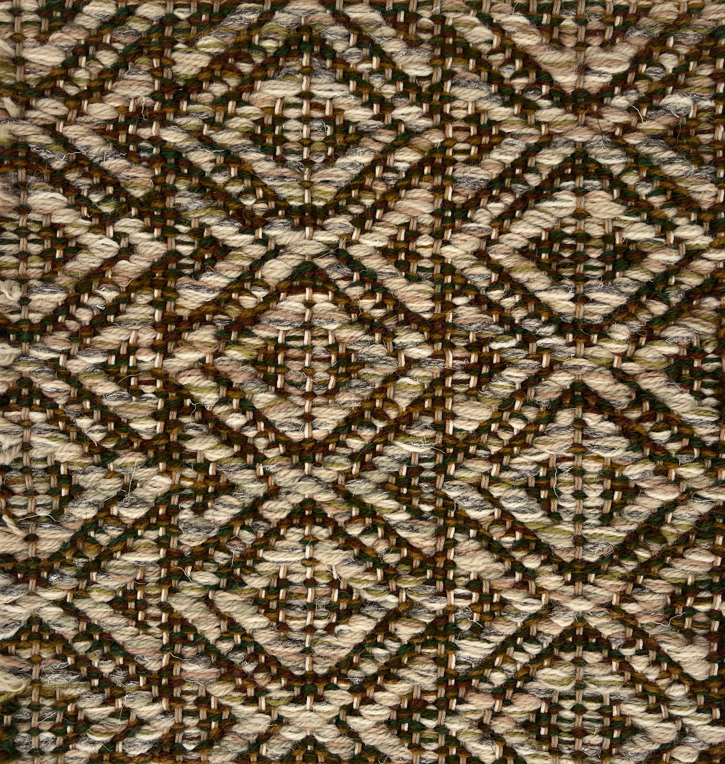 Close-up of a woven rug with diamond pattern in shades of brown.