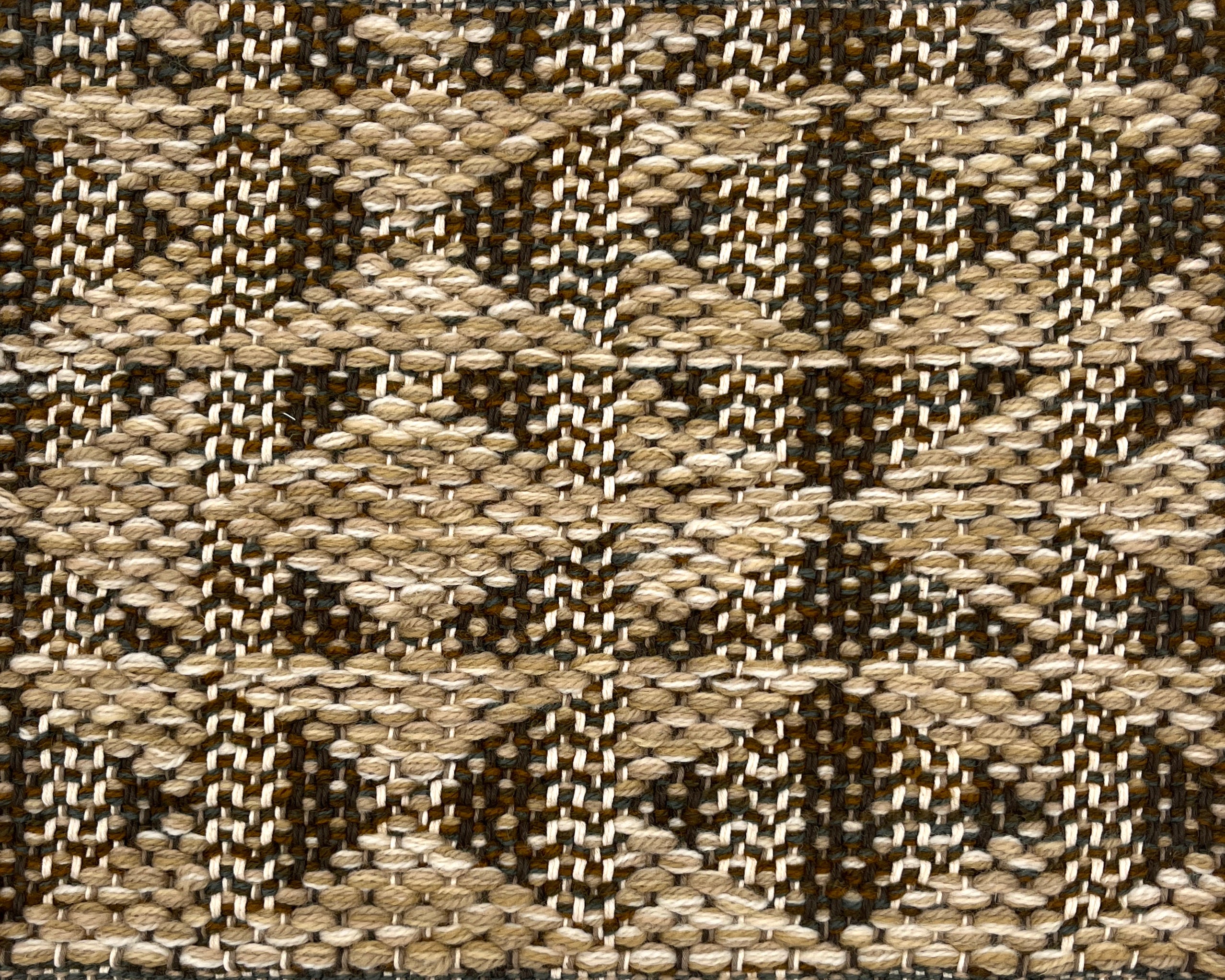 Close-up of a woven rug with geometric pattern in shades of tan and brown.