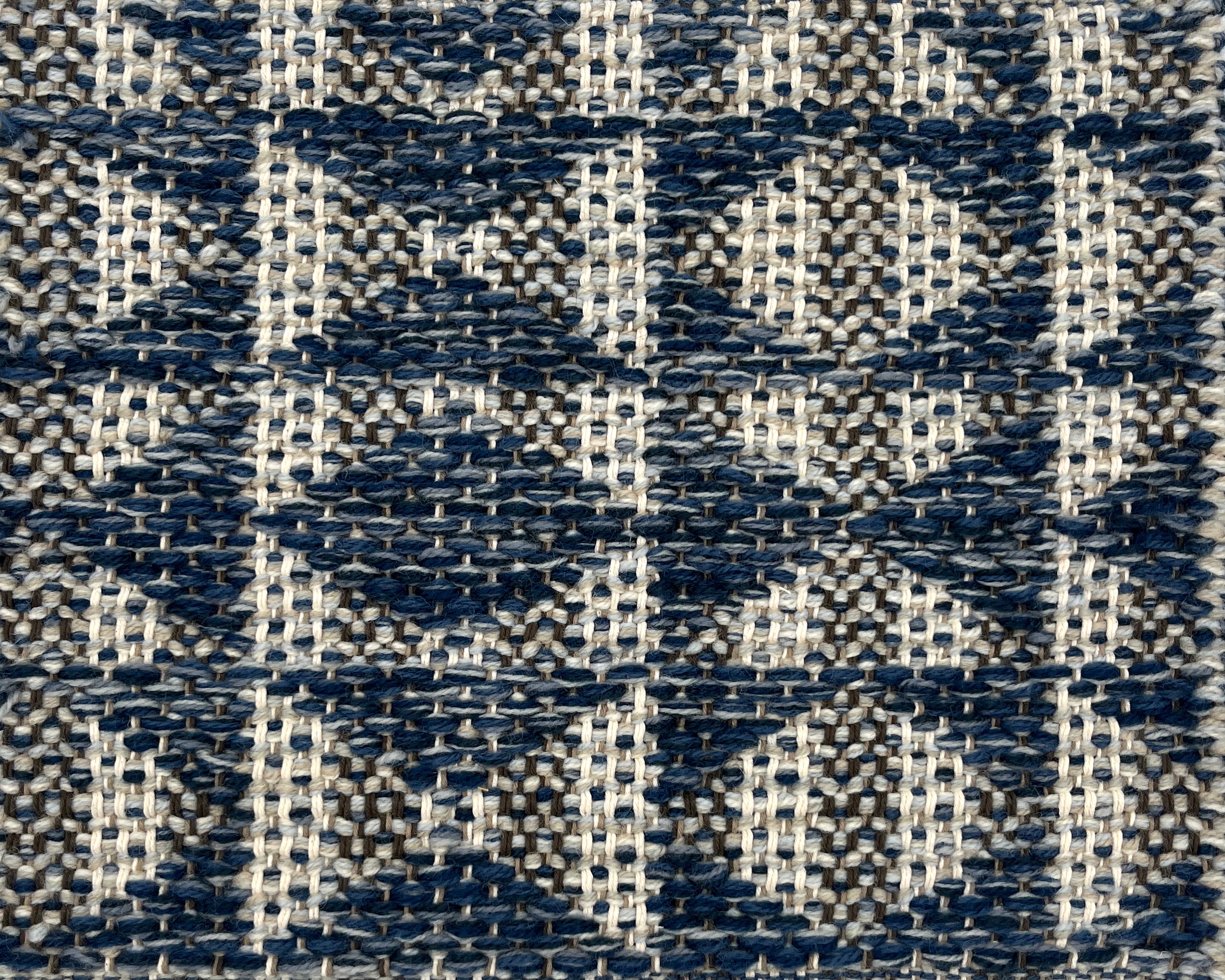 Close-up of a woven rug with geometric pattern in shades of blue.