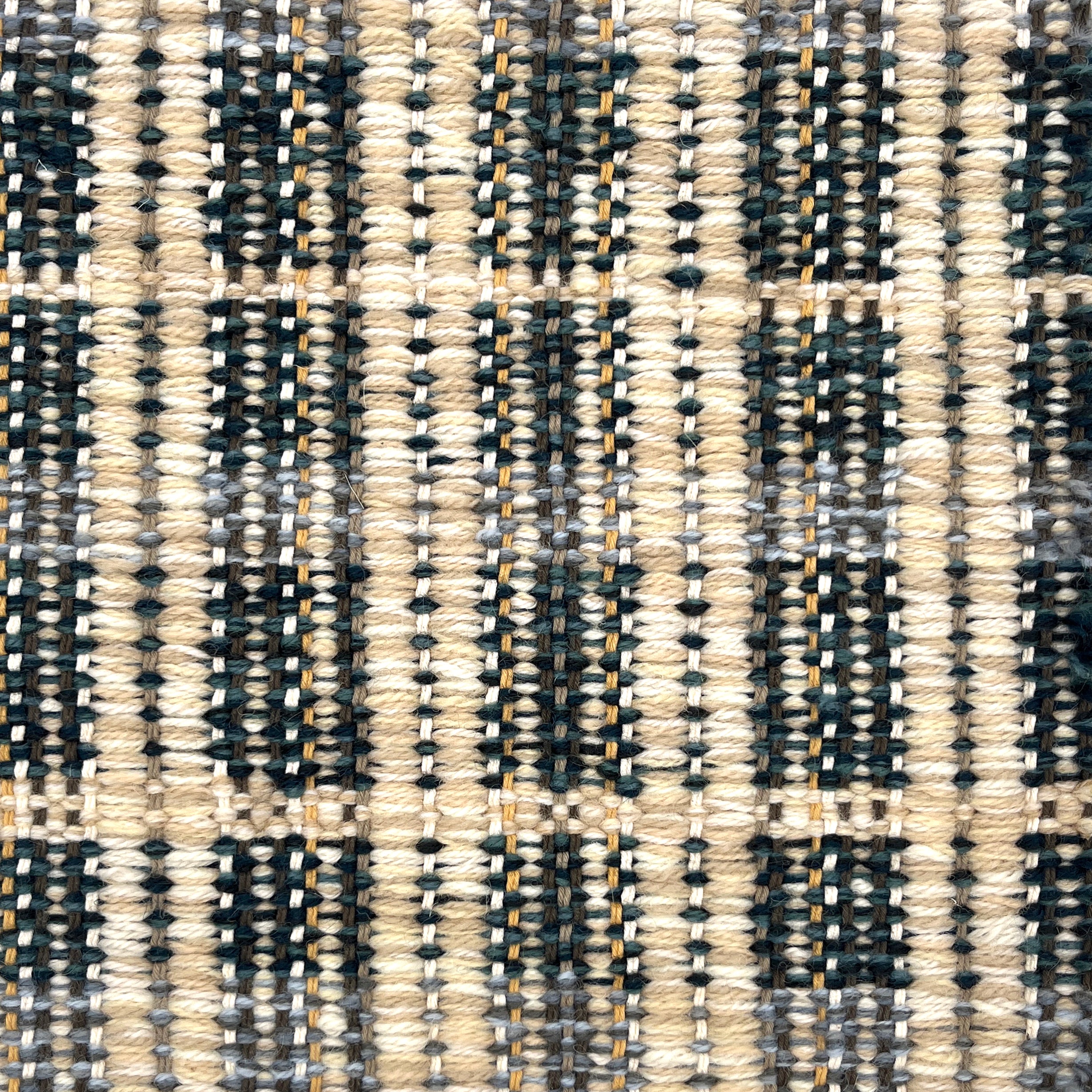 Close-up of a textured teal, cream and beige plaid woven rug. 