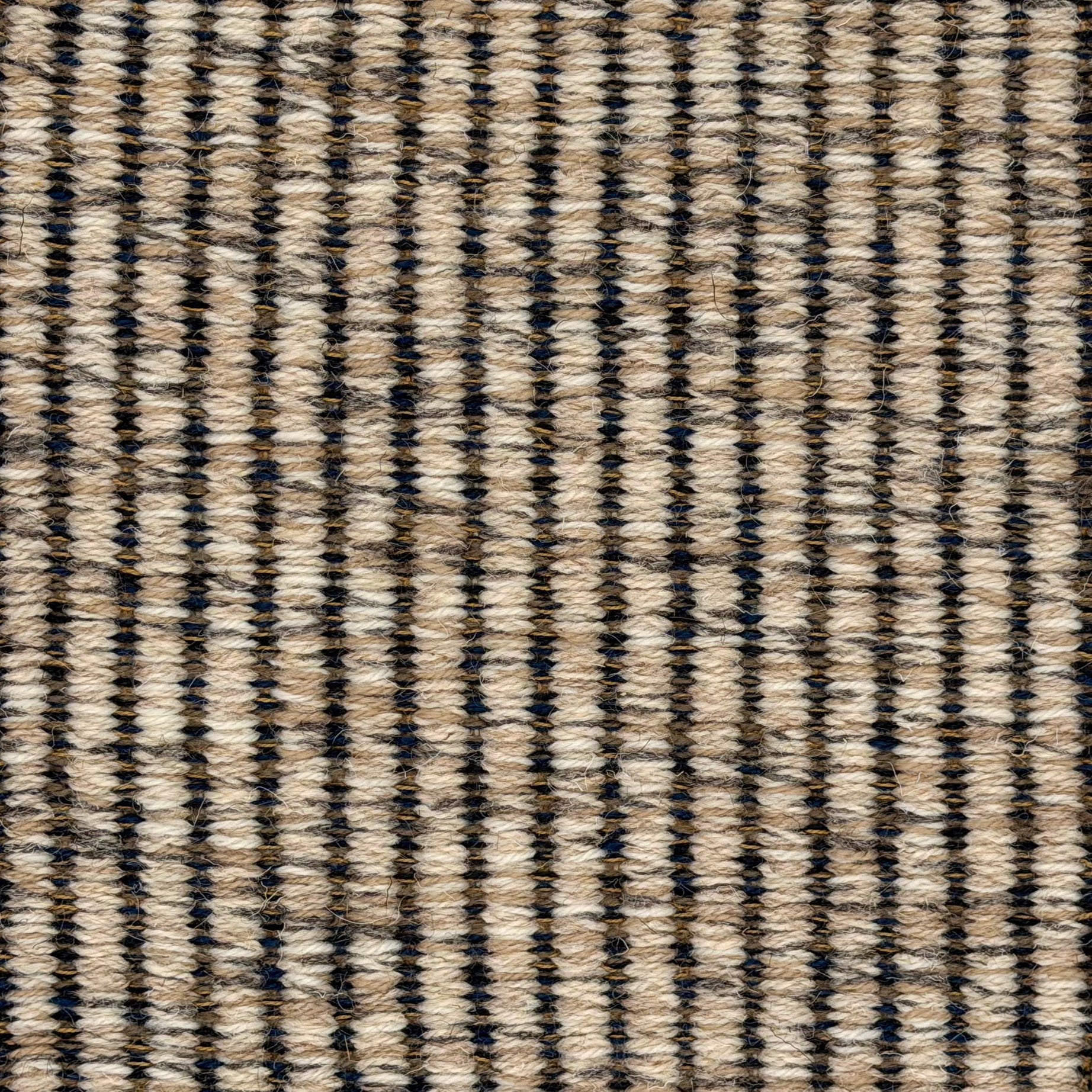 A close-up of a woven wool rug a ribbed stripe in shades of beige and charcoal.