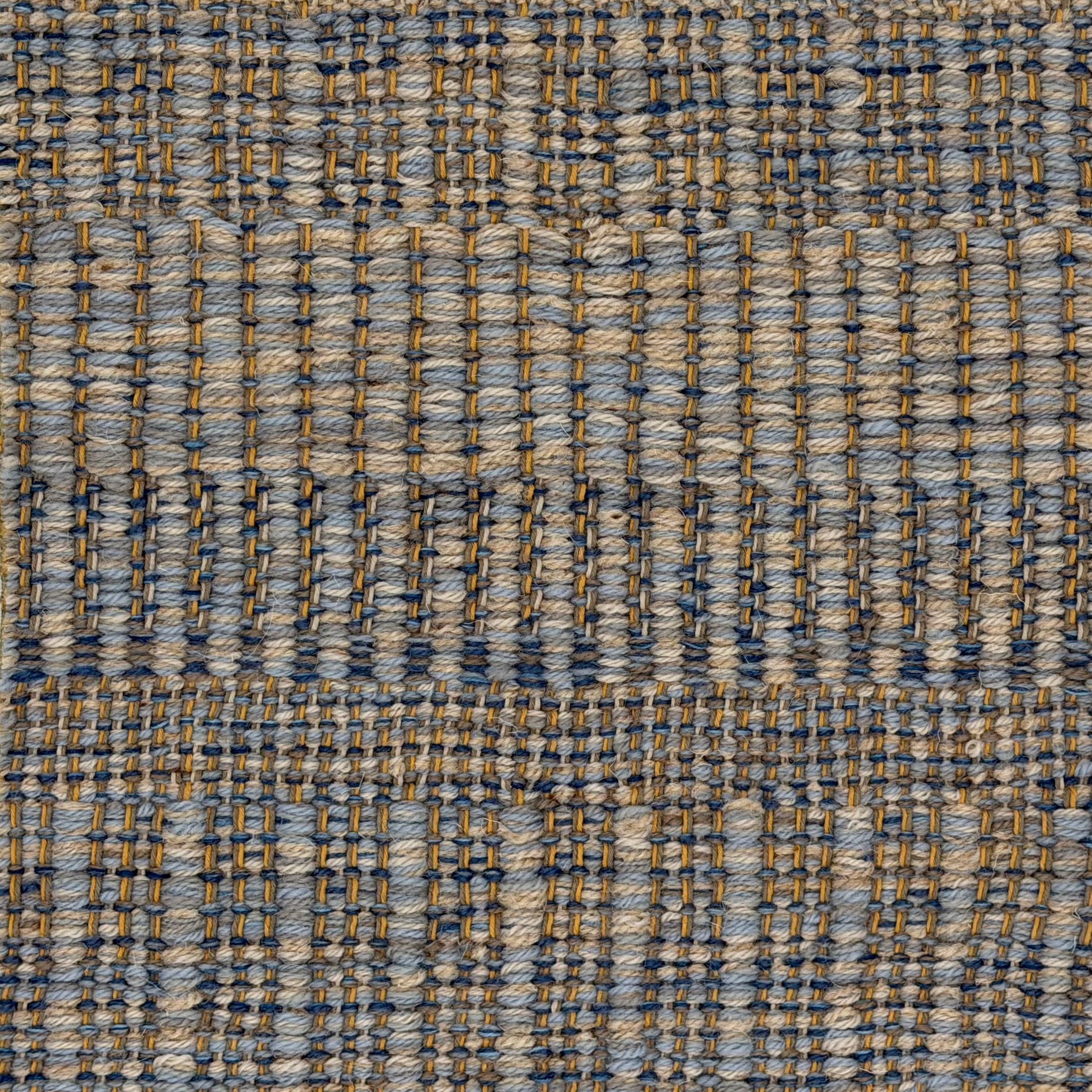 A close-up of a woven rug with a subtle stripe pattern in shades of light blue and tan. 