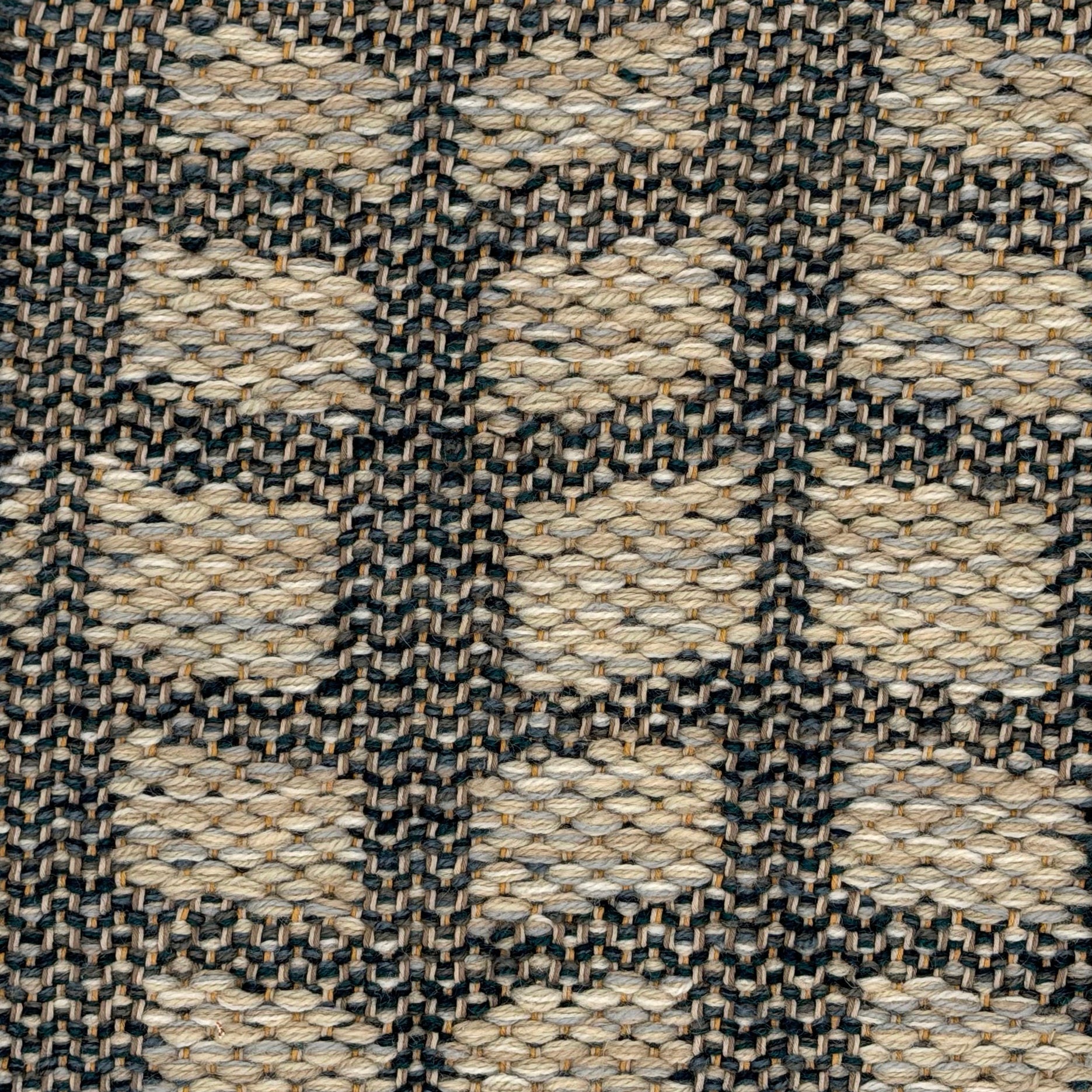 A close-up of a woven wool rug with alternating rectangles in cool beige on a navy blue ground. 
