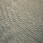 Detail of a wallpaper in an abstract ridged texture in mottled gray and black.