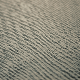 Detail of a wallpaper in an abstract ridged texture in mottled gray and black.