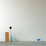 A table with knick knacks stands in front of a wall papered in mottled gold and cream.