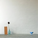 A table with knick knacks stands in front of a wall papered in mottled gold and cream.