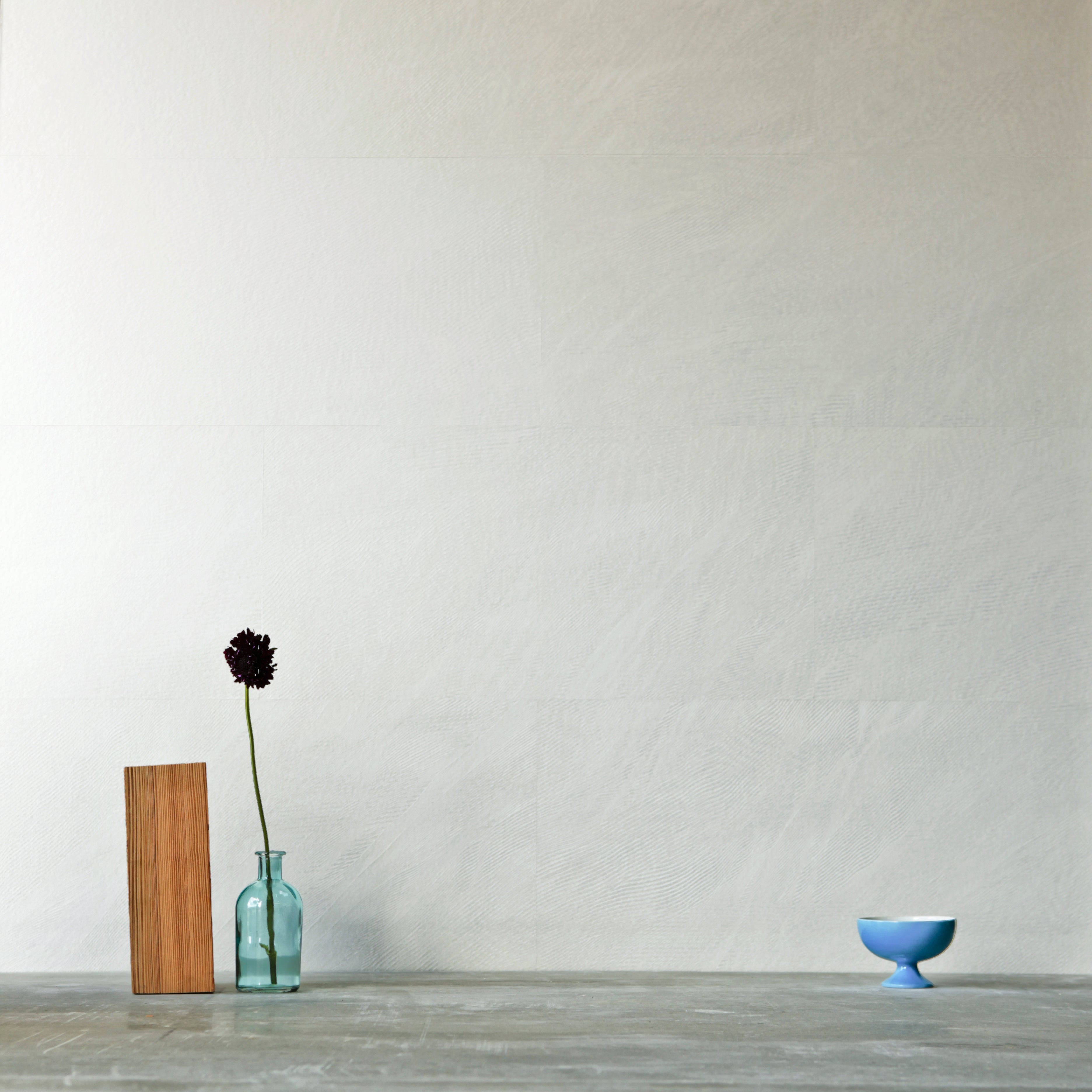 A table with knick knacks stands in front of a wall papered in mottled gold and cream.