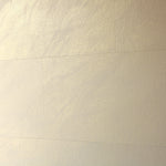 A wall papered in tiles of textured wallpaper in metallic gold and cream.