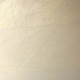 A wall papered in tiles of textured wallpaper in metallic gold and cream.