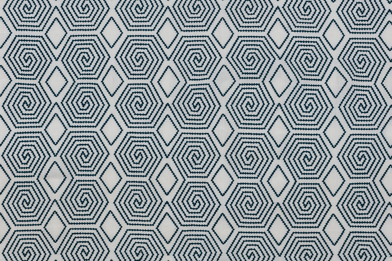 Embroidered fabric with a geometric spiral design in navy on a cream field.