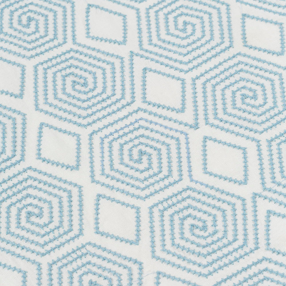 Detail of fabric with a playful embroidered geometric grid print in light blue on a white field.