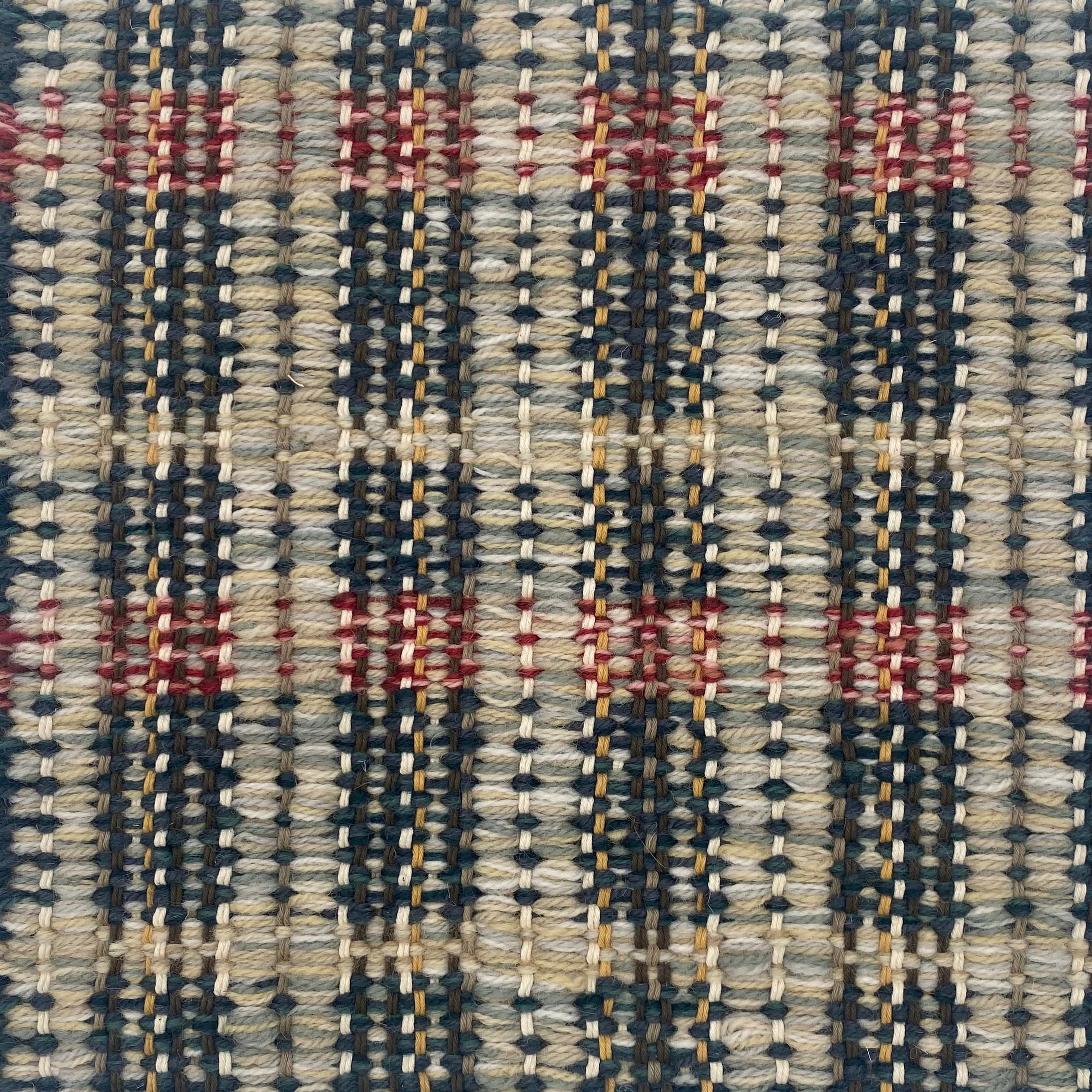 Close-up of a textured rug with a geometric pattern in teal, red and yellow.