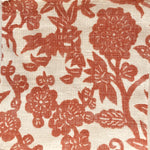 Detail of fabric in a minimalist floral print in red on a cream field.