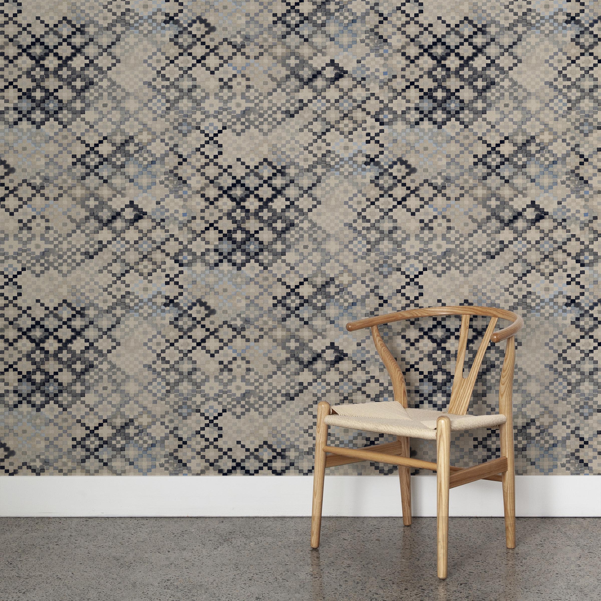 A wooden chair stands in front of a wall papered in a diamond checked pattern in shades of cream, blue and gray.