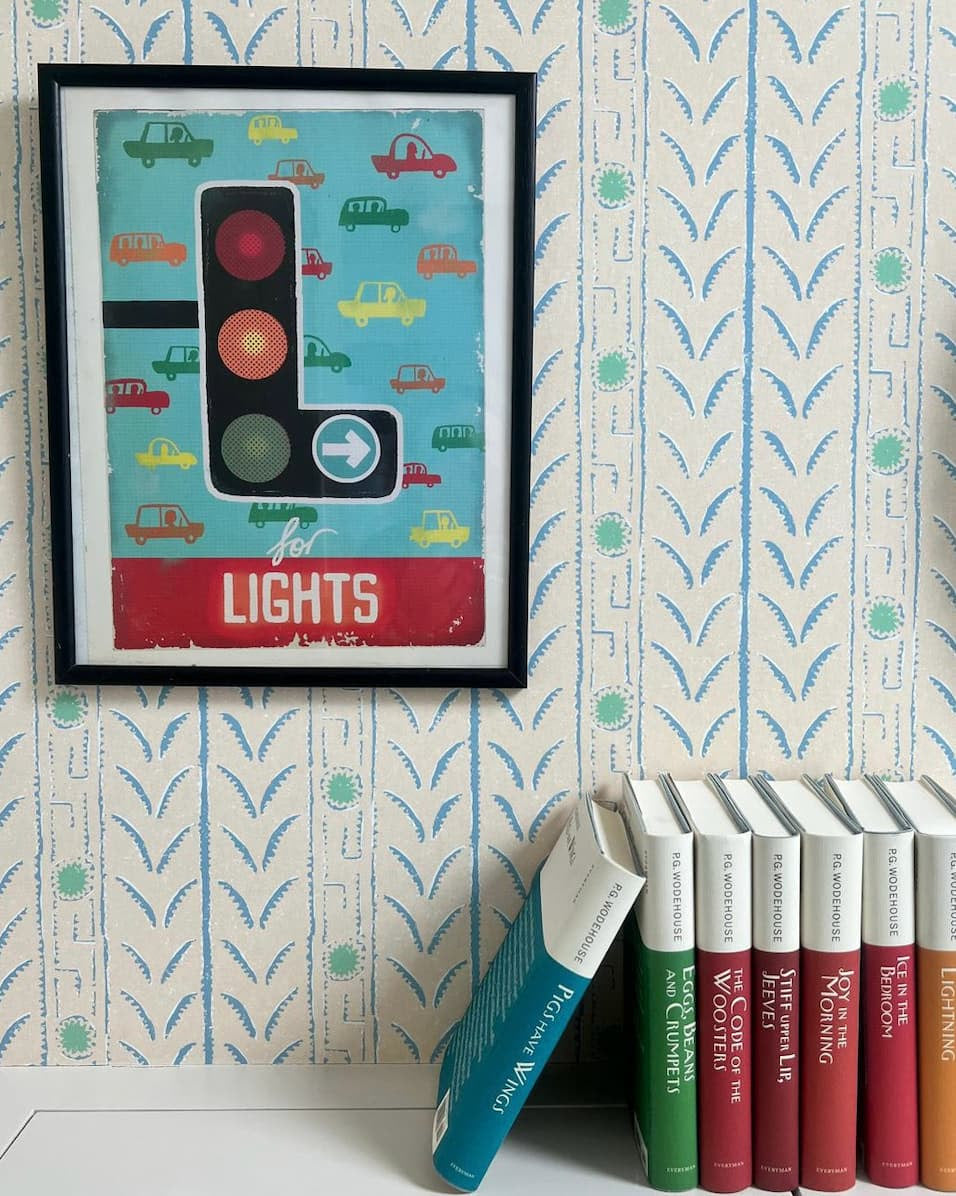 Vignette with colorful books and art against striped wallpaper