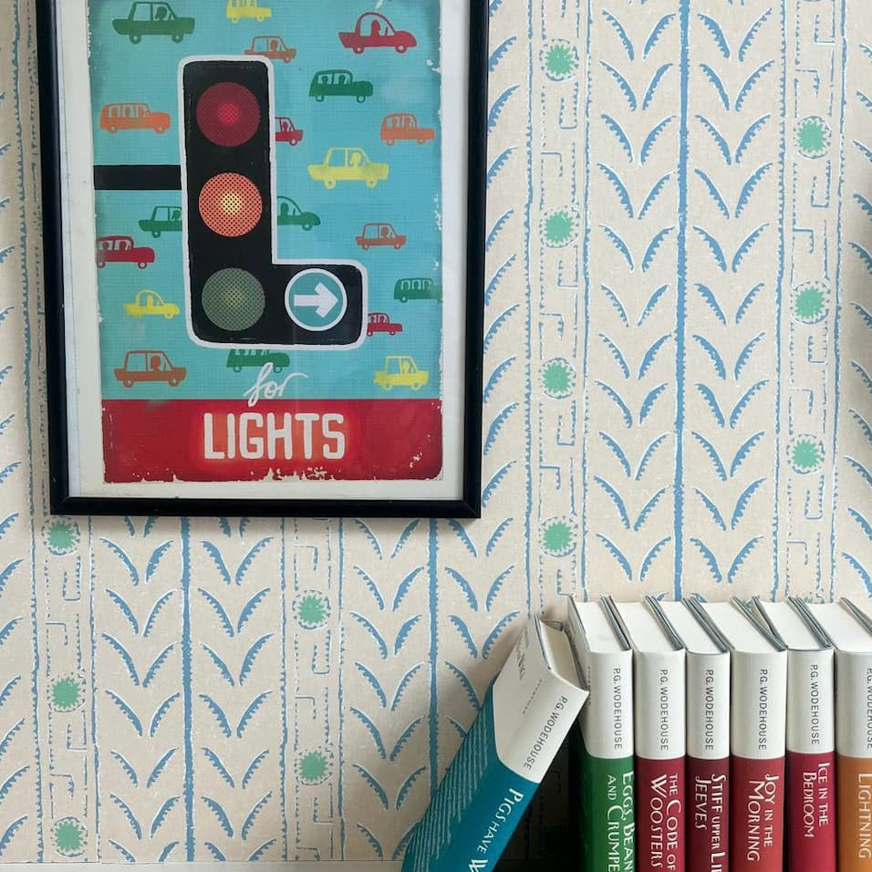 Vignette with colorful books and art against striped wallpaper
