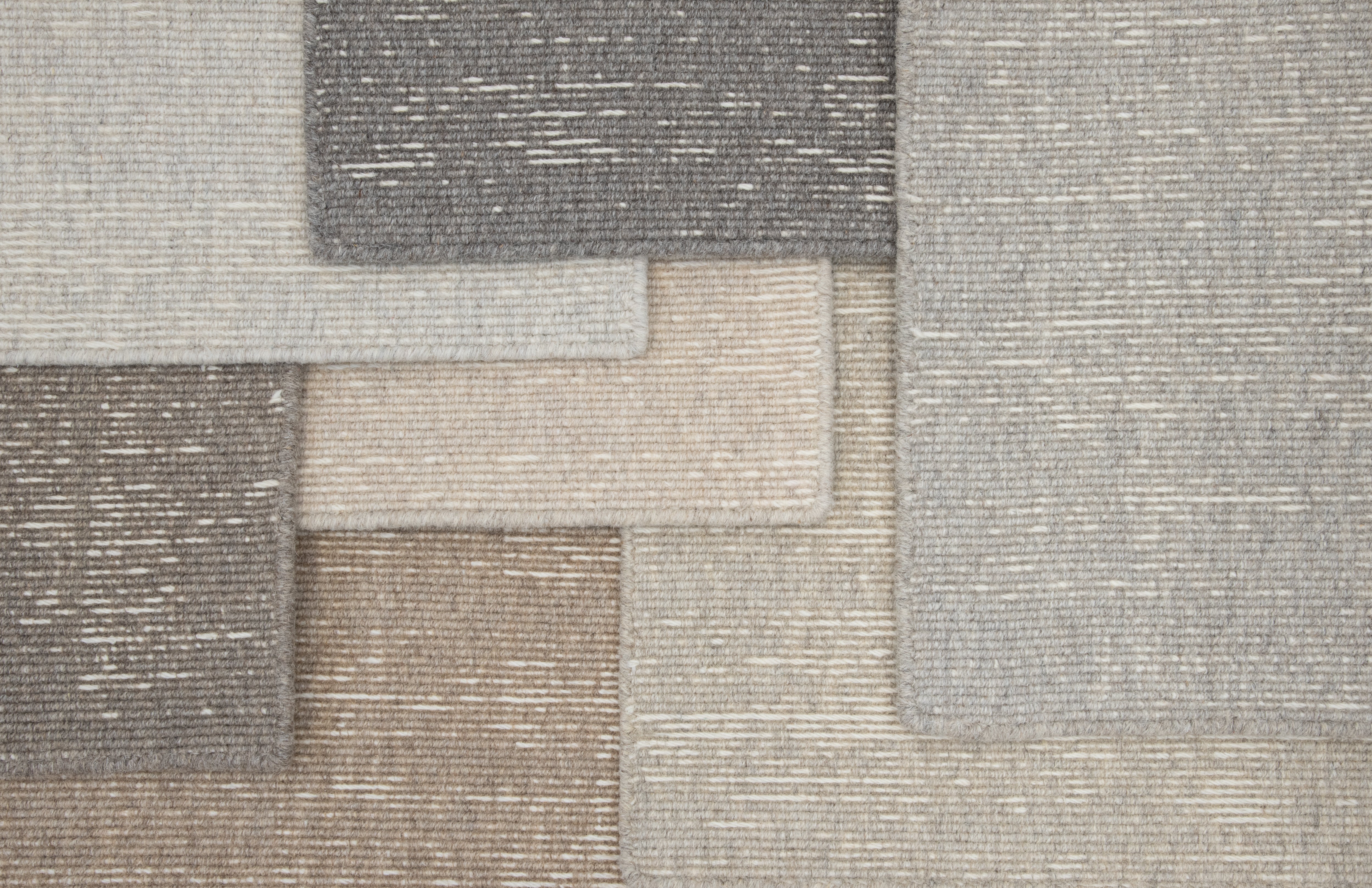 Layered samples of broadloom carpet in neutral colors. 
